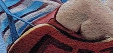 Fresque sur façade. Un garçon joue sur une balançoire au-dessus d'une pile de livres.