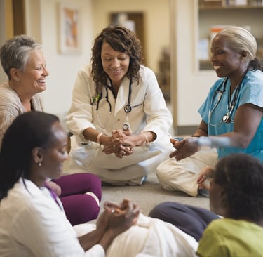 a group of medical providers sitting on the floor in a circle