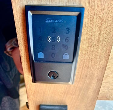 A close up of a wooden door with hand touching a smart lock, representing Jack’s Locksmith local smart locks services