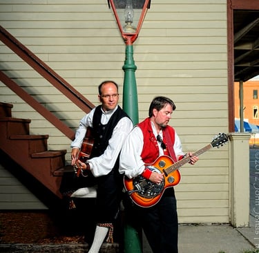 two men hold guitars near a lightest