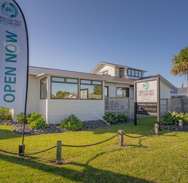 MBO building - white with reflective windows and blue sky with signs Open Now