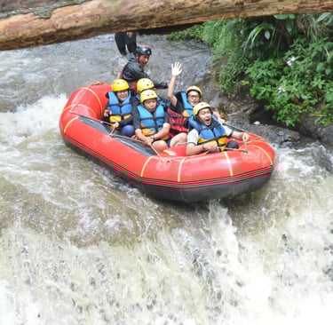 Sekelompok orang di atas perahu karet merah sedang berarung jeram menuruni jeram sungai.