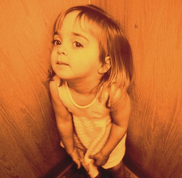 a little girl standing in a corner of a room