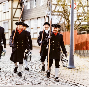 a group of men in uniform uniforms walking down a cobblestone