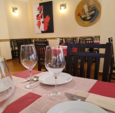 Interior que representa la Historia del Bar Las Tinajas Huelva, con mesas preparadas y un cuadro decorativo al fondo.