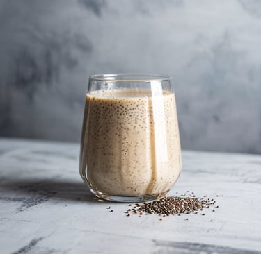 Glass of vanilla chia protein smoothie on a light textured surface with a small pile of chia seeds