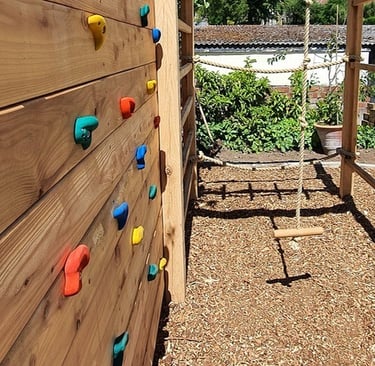 Bespoke climbing frame with monkey bars, climbing wall, rope swing in a family garden design