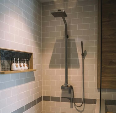 Walk-in shower with matte black fixtures and recessed shelf on subway-tiled wall