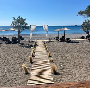 Wooden walkway leading to a beachfront wedding arch with sunbeds and umbrellas on a sandy beach.