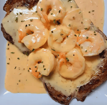 a plate of carne asada with shrimp in seafood sauce