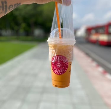 a person holding a cup of coffee in a plastic cup