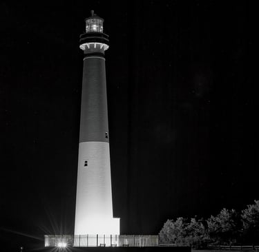 A black-and-white, minimalist photo of the Barnegat Lighthouse at night.