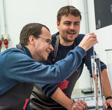 two men standing in front of a chalkboard, ginebra, mallorca, ginebra artesana, marca person