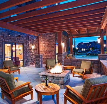 a patio with a fire pit and chairs