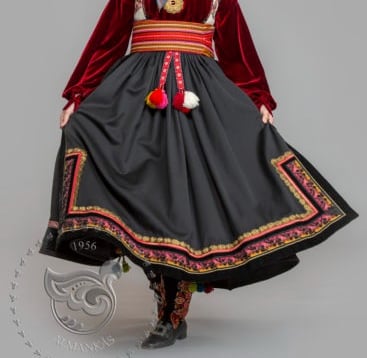 A woman in a bunad with a velvet shirt and wide belt