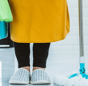 a woman in a yellow dress holding a mop and cleaning supplies