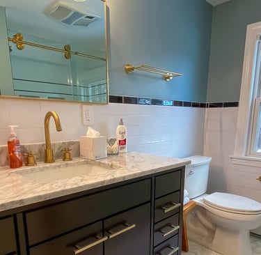 Bathroom vanity and white stone countertop with brass accesories