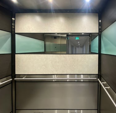 elegent elevator interior with cream and brown wall panels, a mirror and round handrails