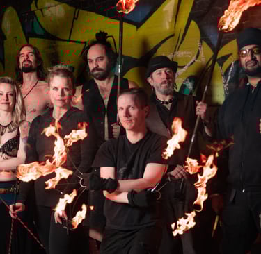 Flame Syndicate poses in front of a wall full of graffiti art