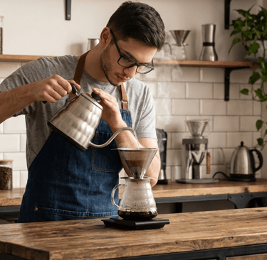 barista fazendo usando filtro de café inox. está em uma cozinha aconchegante com metro white