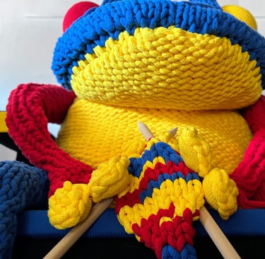FROG knitting on Rietveld chair with giant knitting needles by Dundee & Lee