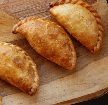 a wooden cutting board with three pastries on a cutting board