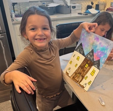 Smiling young artist showing her painted house artwork at Kelley's Neighborhood Art