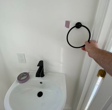 Hanging towel right over pedestal sink in bathroom performing handyman tasks