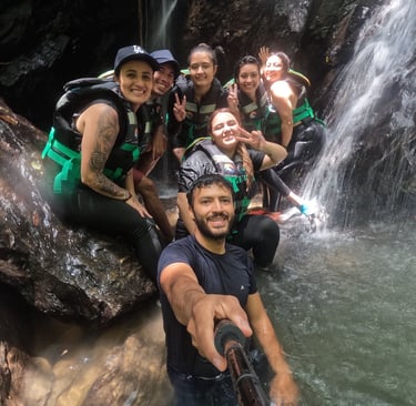 Un grupo de viajeros felices con chalecos salvavidas se toma una selfie bajo una cascada tropical 