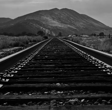 a train track with a mountain in the background taken by Jordan Boyle of JJ Everitt Photography
