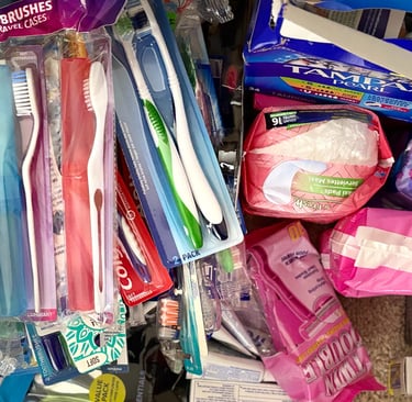 a bunch of toothbrushes and toothpaste in a pile of various hygiene products