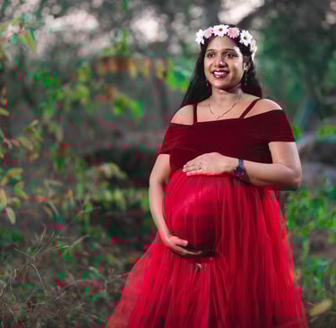 "Pregnant woman in a flowing gown holding her baby bump, radiating joy and love in a serene outdoor 