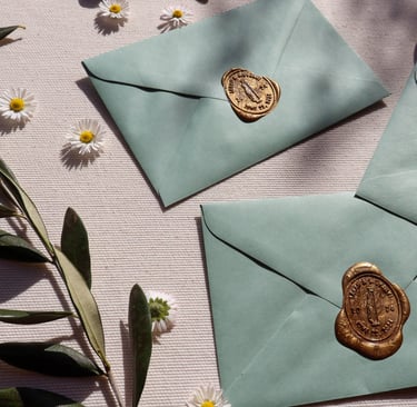 sage green envelopes with custom wax seal flowers and olive branches