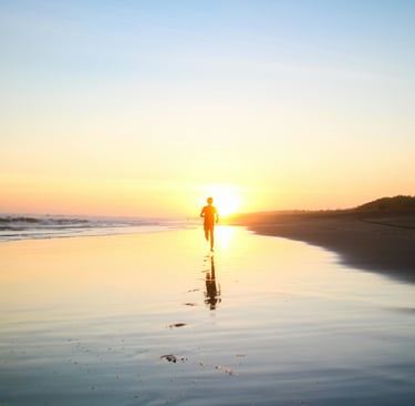 a person walking on a beach at sunset