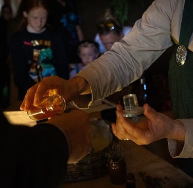 a person is holding a glass bottle places a drop of tincture onto the back of another person's hand