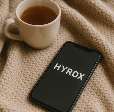 A cozy blanket, a steaming cup of tea, and a phone with message "HYROX" on the screen