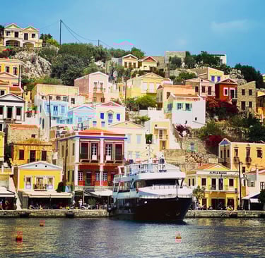 Colorful neoclassical houses on a hillside overlooking a ferry at Symi Island harbor in Greece.