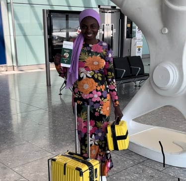A Nigerian girl wearing a colourful dress, holding a Nigerian passport in an airport in London