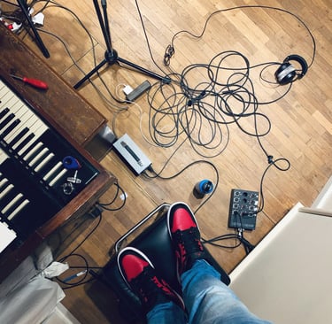 Studio floor with cables, Hammond keys and red sneakers visible