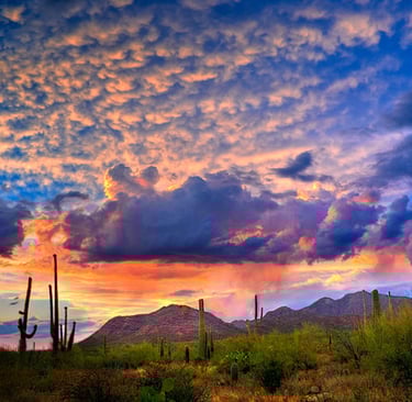 a sunset sky with clouds and mountains in the background