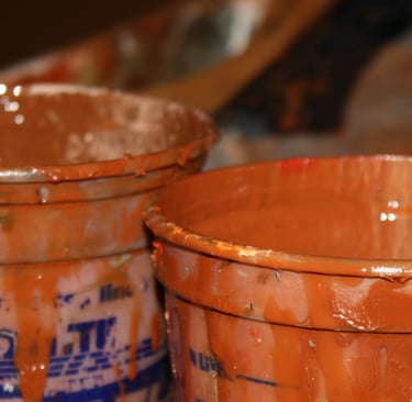 two buckets with paint and a paintbrush in the background