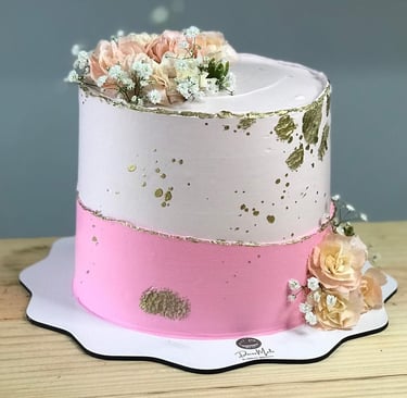Bolo decorado em camadas com rosas, flores brancas e detalhes dourados, perfeito para festas e comem