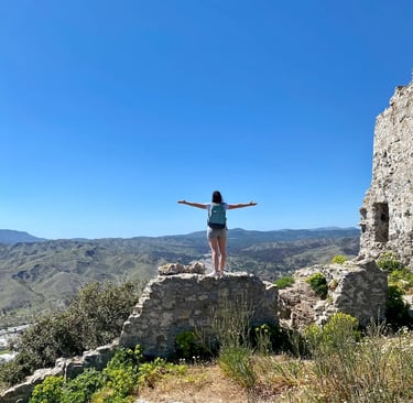 a woman standing on a rock formation with her arms outstretched out