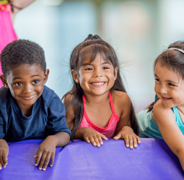 three young children in colorful gym attire are smiling and posing for a picture