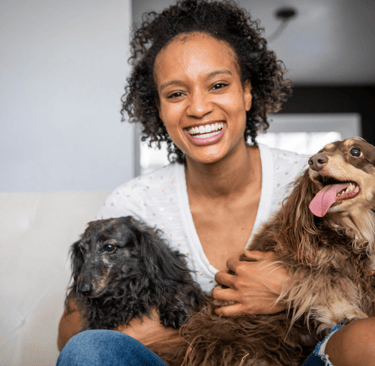 A beautiful young black woman holding her two elderly dogs