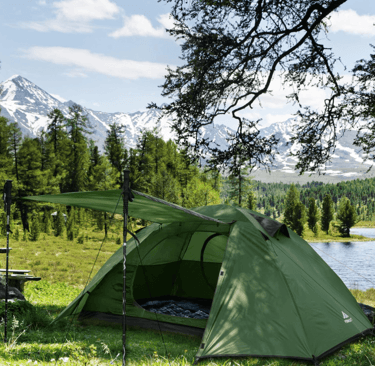 a tent pitched up in a field with a picnic table and chairs