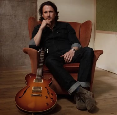 Professional guitarist from Mosaic sitting with a hollow-body electric guitar for an acoustic set