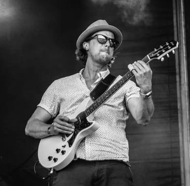 Lead guitarist of Mosaic performing a high-energy country-rock solo at a festival-style wedding