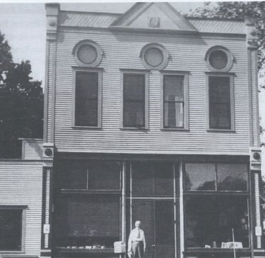 a two story white building with a man standing in front of it