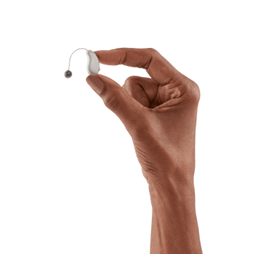 Pessoa segurando uma aparelho auditivo discreto na mão